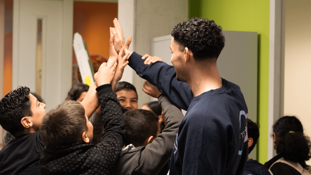Vrijwilliger omringt door een groep kinderen die allemaal een high five geven
